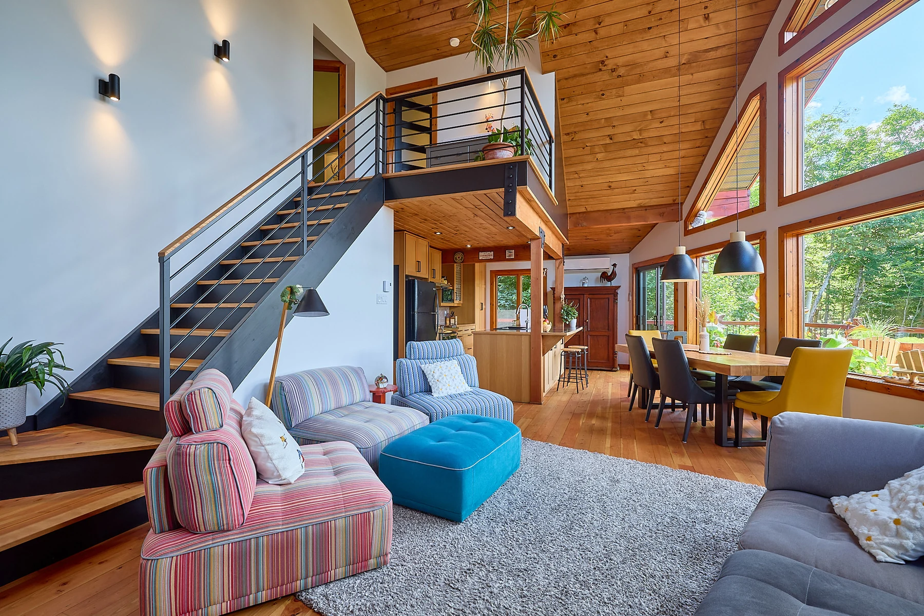 Salon de chalet à double hauteur, grandes fenêtres et plafond de bois, photographié par Jonathan Beaupied
