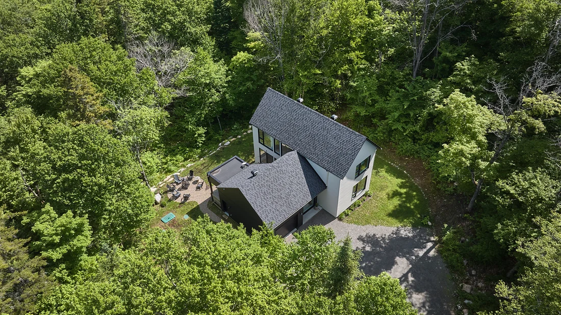 Vue aérienne d’une résidence contemporaine entourée d’une forêt dense, par Jonathan Beaupied